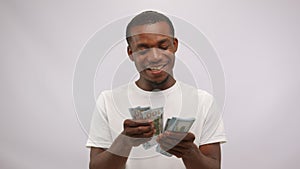 Happy smiling blessed african american man counting dollars on white background.