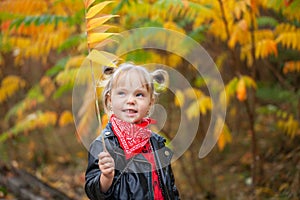 Happy smiling blonde girl holding yellow red leaves in sunny autumn park