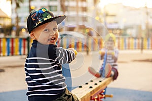 Happy smiling boy on balance swing. children playing at city playground. copy space