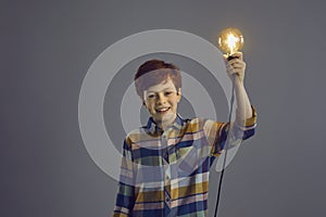 Happy smiling boy child holding glowing lightbulb lamp above head headshot