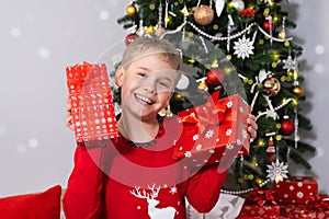 Happy Smiling Boy with Christmas gift Boxes Near Christmas Tree.