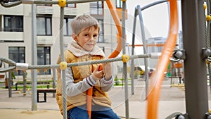 Happy smiling boy enjoys spinning on carousel at new public playground. Active child, sports and development, kids playing