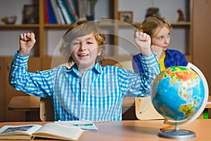 Happy smiling boy on the geography lesson in school classroom. Educational concept