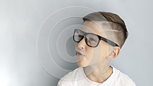 Happy smiling boy in glasses. Kid indoors of the class room with blackboard on a background.