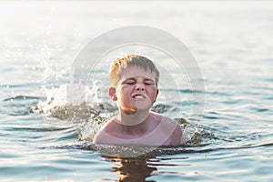 Happy smiling boy having fun swimming in the water.Cute boy swimming in water. Summer vacation
