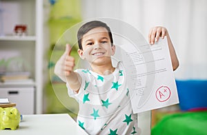 Happy smiling boy holding school test with a grade