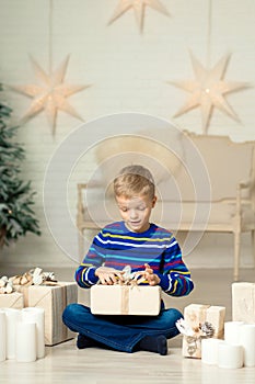Happy smiling boy holds christmas gift box against the background of New Year`s decor