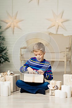 Happy smiling boy holds christmas gift box against the background of New Year`s decor