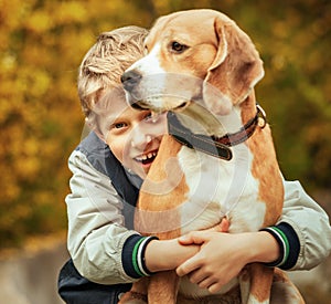 Happy smiling boy hugs his best freind beagle dog