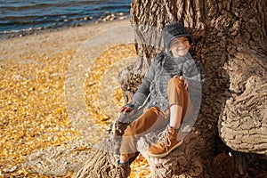 Happy smiling boy sitting on the tree at the beach