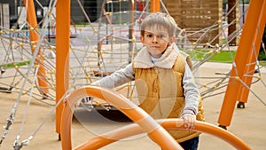 Happy smiling boy spinning on carousel at the public playground. Active child, sports and development, kids playing outdoors