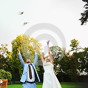 Happy smiling bride and groom hands releasing white doves on a s