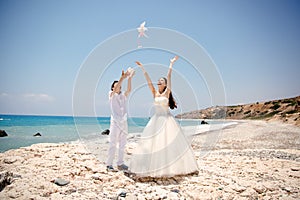 Happy smiling bride and groom hands releasing white doves on a sunny day. Mediterranean Sea. Cyprus