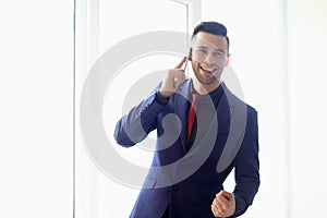 Happy smiling business man talking on cell phone in the office