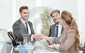 Happy smiling business people shaking hands after a deal in offi