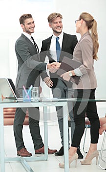 Happy smiling business people shaking hands after a deal in offi