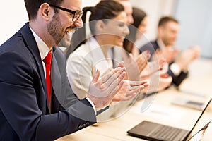 Happy smiling business team clapping hands during a meeting