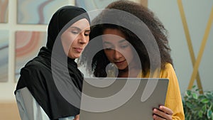 Happy smiling business women multiracial businesswomen colleagues talk discuss online project on laptop Arabian Muslim