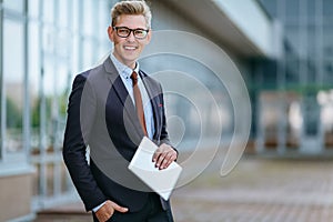 Happy smiling businessman with digital tablet. Portrait of a Male executive manager in trendy clothes with tablet PC in