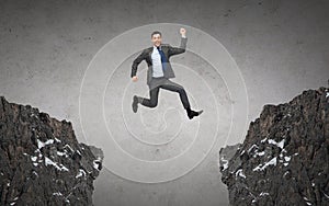 Happy smiling businessman jumping between rocks