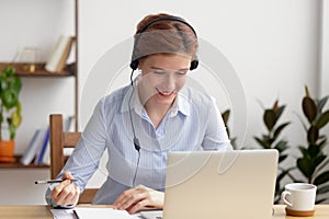 Happy smiling businesswoman in headphones self-study at office desk