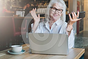 Happy smiling businesswoman sitting at table in front of laptop,holding hands up,working, learning.