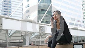Happy smiling businesswoman sitting talk on mobile phone outside street city near office
