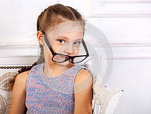 Happy smiling calm kid girl in eyeglasses looking. Closeup studio portrait