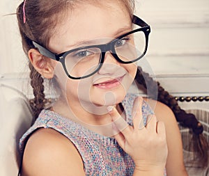 Happy smiling calm kid girl in eyeglasses looking and thinking a