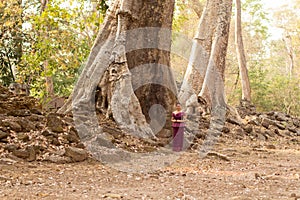 A Happy Smiling Cambodian Asian Girl in Traditional Dress Standing by an Old Tree in Angkor Thom