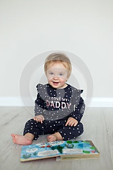 Happy smiling caucasian baby girl with lights garland sitting on the floor photo