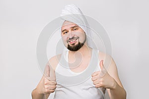 Happy smiling Caucasian bearded man in whilte t-shirt and with a towel on his head posing to camera on isolated while