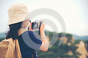 Happy smiling caucasian children asian girl backpack and holding camera for take a photo check in on mountain.