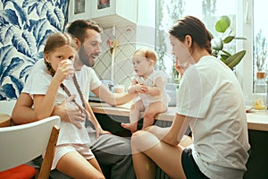 The happy smiling caucasian family in the kitchen preparing breakfast