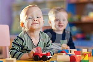 Happy smiling caucasian kids are playing with educational toys in nursery