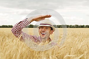 Happy smiling caucasian man farmer standing proud in front of his wheat fields looking in his future