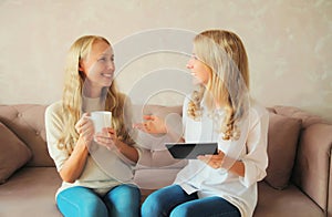 Happy smiling caucasian middle aged mother and adult daughter, women talking and looking at each other together sitting on couch