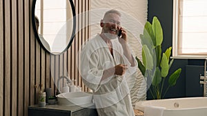 Happy smiling Caucasian retired elderly man talk smartphone friendly call make distant order speak cellphone senior