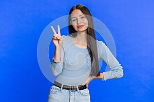 Happy smiling Caucasian woman showing victory sign, hoping for success and win, doing peace gesture