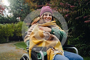 Happy smiling cheerful Caucasian girl on a wheelchair relaxing alone in autumn garden park