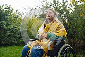 Happy smiling cheerful Caucasian girl on a wheelchair relaxing alone in autumn garden park