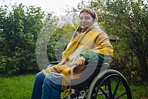 Happy smiling cheerful Caucasian girl on a wheelchair relaxing alone in autumn garden park