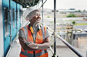 A happy, smiling and cheerful young black woman or senior construction industry worker standing at a building site. A