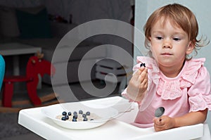 Happy, smiling child eating oatmeal with berries. The concept of a healthy breakfast for children, porridge with blueberries on