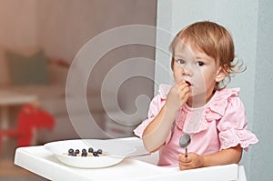 Happy, smiling child eating oatmeal with berries. The concept of a healthy breakfast for children, porridge with blueberries on