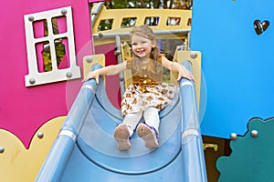 Happy Smiling Child Girl Playing At Playground Outdoors In a nice Park on a slide