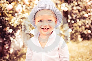 Happy smiling child on the green grass in summer park. Baby face closeup. Funny little kid boy close up portrait. Blonde