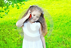 Happy smiling child talking on smartphone in summer