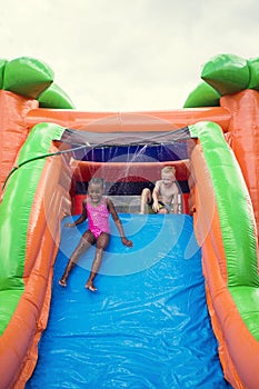 Happy smiling children playing on an inflatable slide bounce house