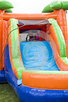 Happy smiling children playing on an inflatable slide bounce house